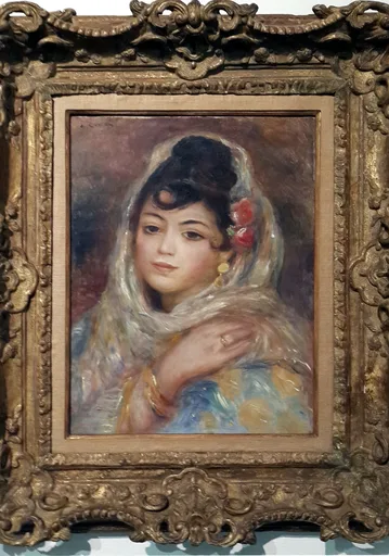 A dark haired woman in a white lace headscarf and blue floral shawl rests one hand on her shoulder, with a red flower tucked into her hair