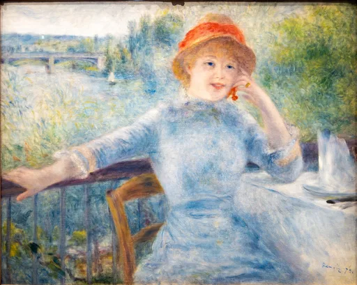 A smiling woman in an orange hat and pale blue dress leaning on a riverside railing beside a table, with a bridge over the water behind her