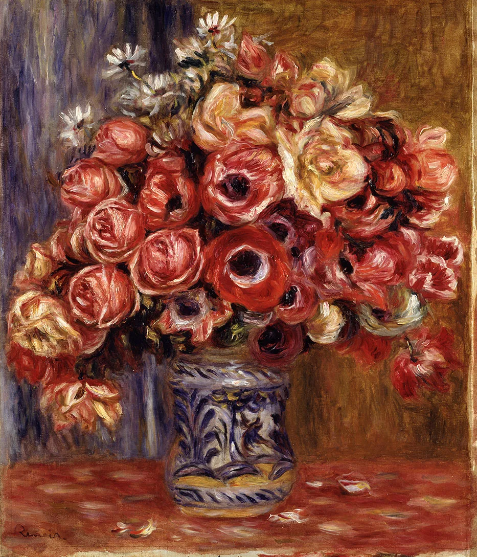 A dense bouquet of red anemones, pink roses, and white daisies in a blue and white patterned vase on a red tablecloth