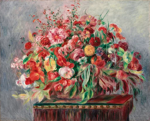 A lush basket overflowing with red, pink, and white flowers on a dark red table against a pale grey wall