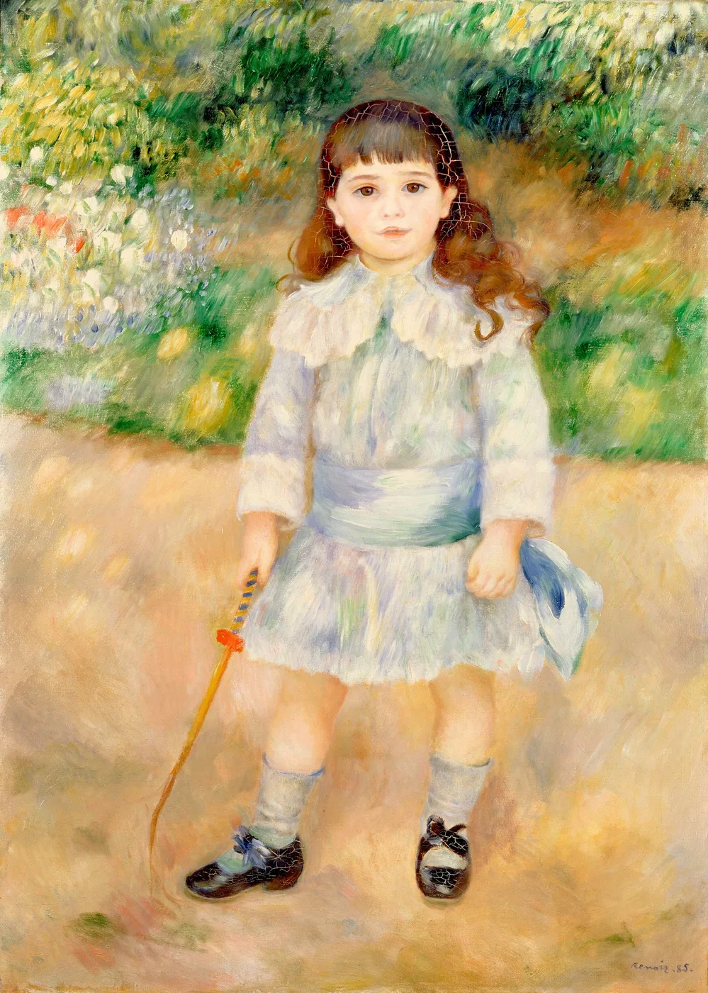 A young child in a pale blue dress standing in a garden path, holding a whip in one hand and a hat in the other, amid green foliage and flowers
