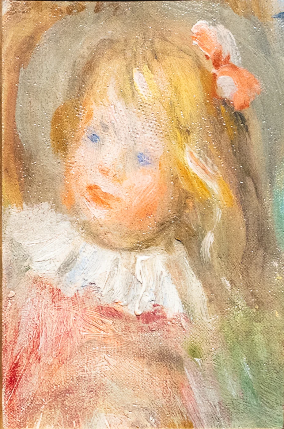 Close-up portrait of a small blond child in a red dress with white lace collar and a pink bow in her hair.