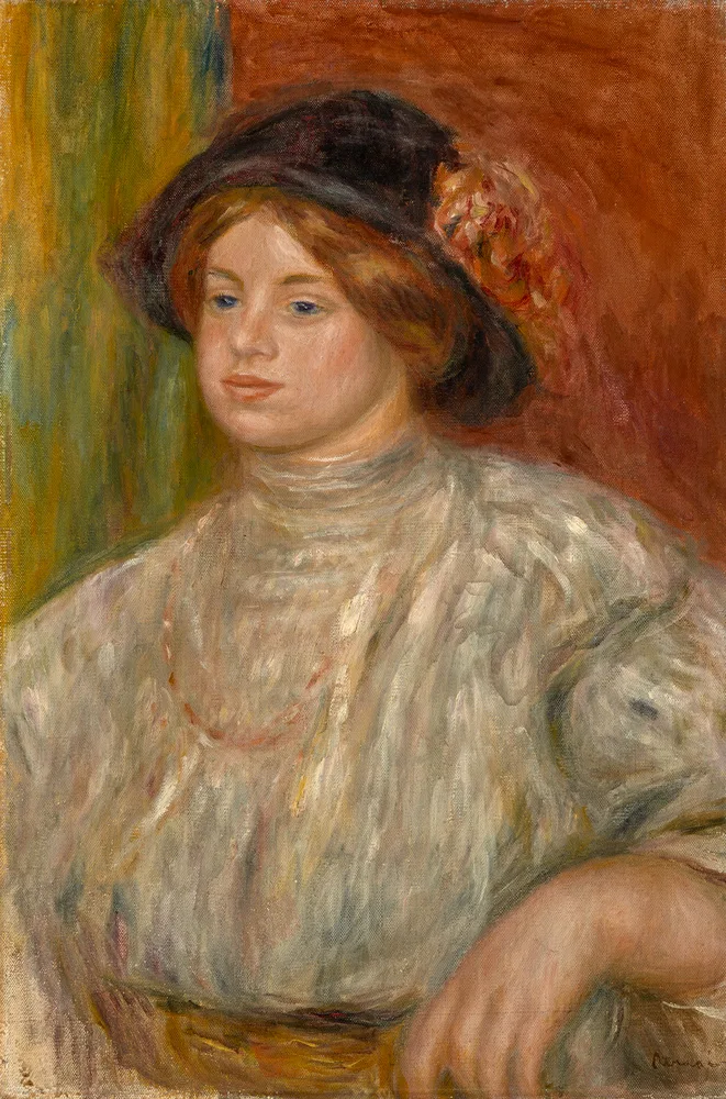 A young woman in a wide dark hat with pink flowers and a loose white blouse, resting her arm on a chair against a warm red backdrop