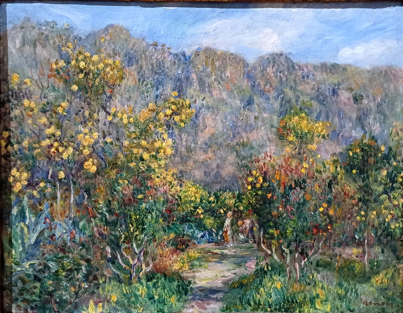 Yellow mimosa blossoms line a garden path before jagged grey mountains, small figures walking beneath a blue sky.