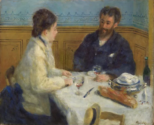 A man and woman sit close together at a set table sharing food and wine in a restaurant, with tan wood paneling and pale blue patterned wallpaper behind them