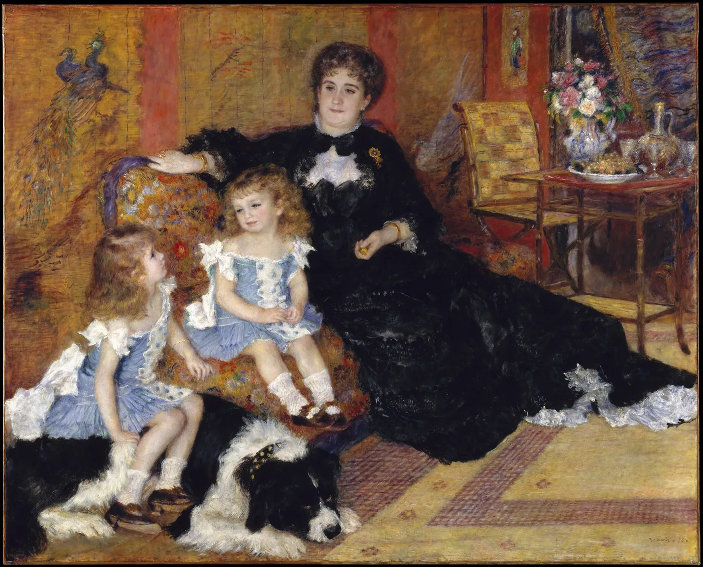 A seated woman in black lace holds two young girls in blue dresses on a floral sofa, a black and white dog at their feet