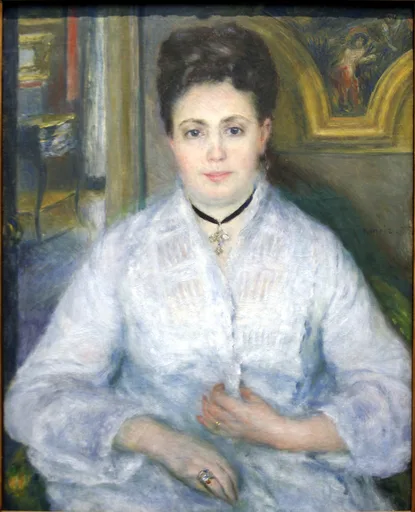 A seated woman with dark upswept hair in a pale blue dress and pendant necklace, hands folded, in an interior with a gilt-framed painting