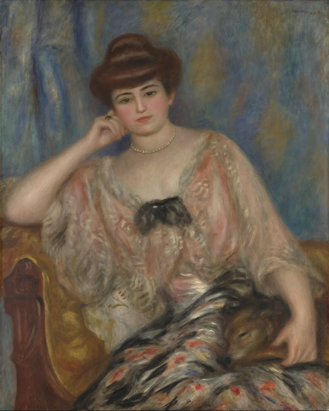 A seated woman in a sheer patterned blouse and pearl necklace rests her head on one hand, her other arm resting on a fur-trimmed throw over the armchair.