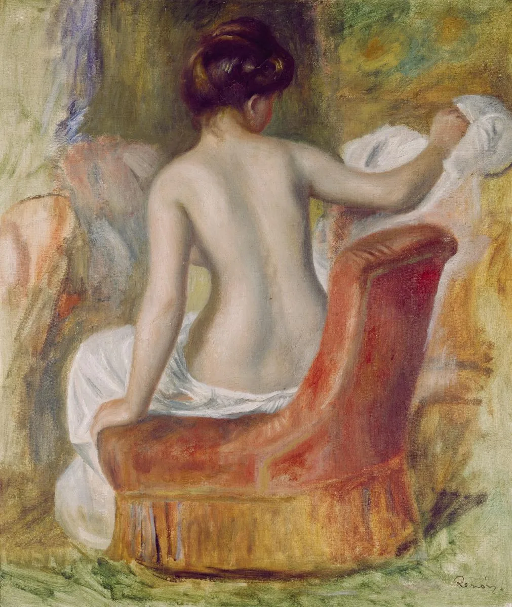 A nude woman seen from behind, hair pinned up, leans over a red armchair reaching for white cloth.