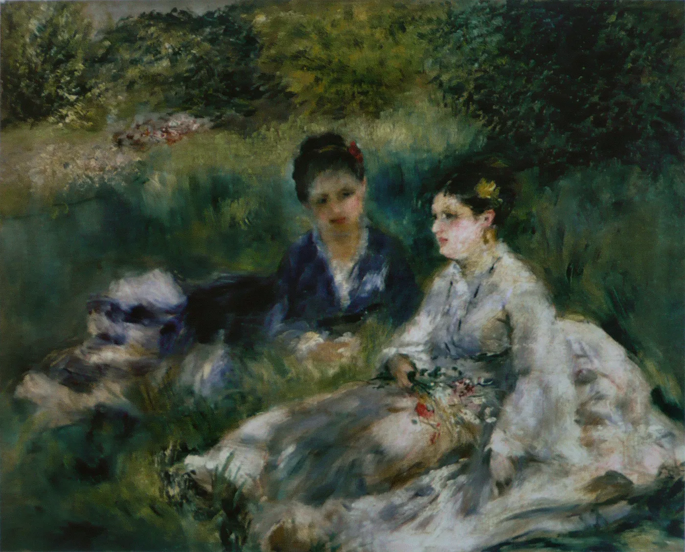 Two women sit together on the grass, one in a dark blue dress, the other in white holding flowers, deep green foliage around them.