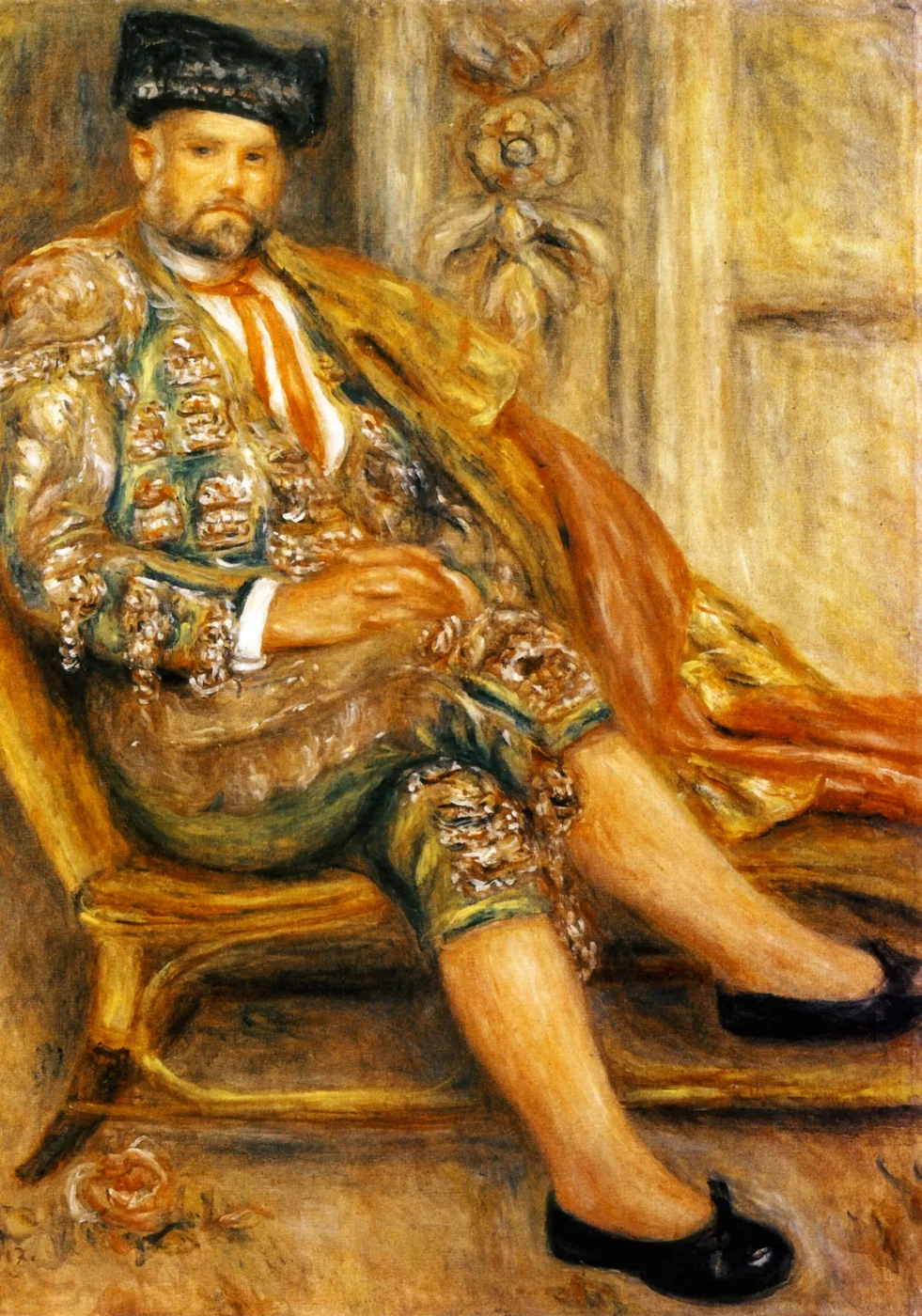 A bearded man in an embroidered toreador costume and black cap sits with legs crossed in an armchair, painted in gold, ochre, and green.