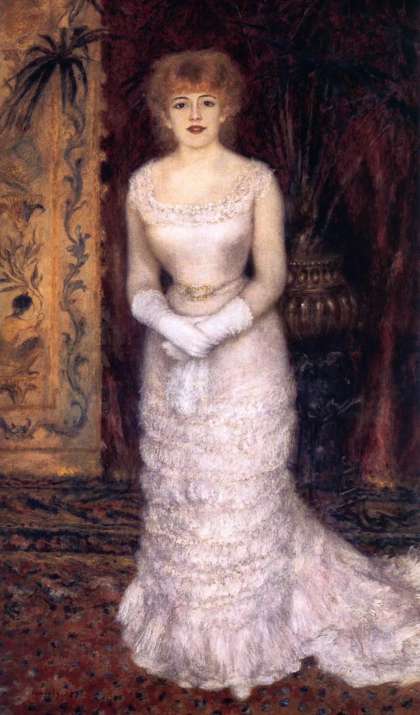 A red-haired actress in a long pale pink gown and white gloves standing before a dark potted palm and an ornate screen, in blush pink and deep maroon