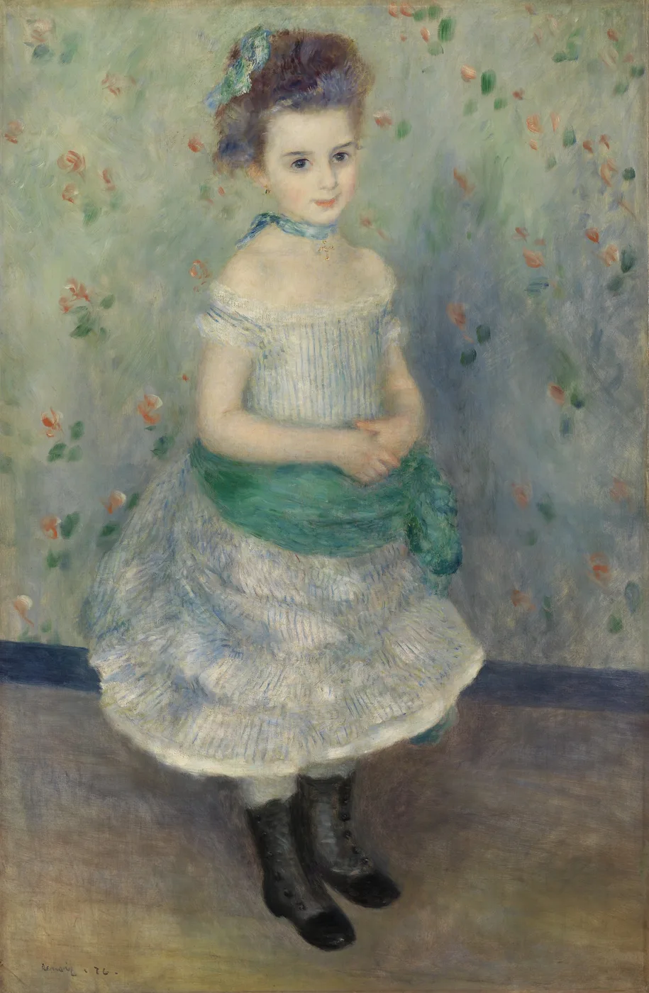 A young girl in an off shoulder striped dress with a green sash and black boots stands against a floral wallpaper of pale green and pink