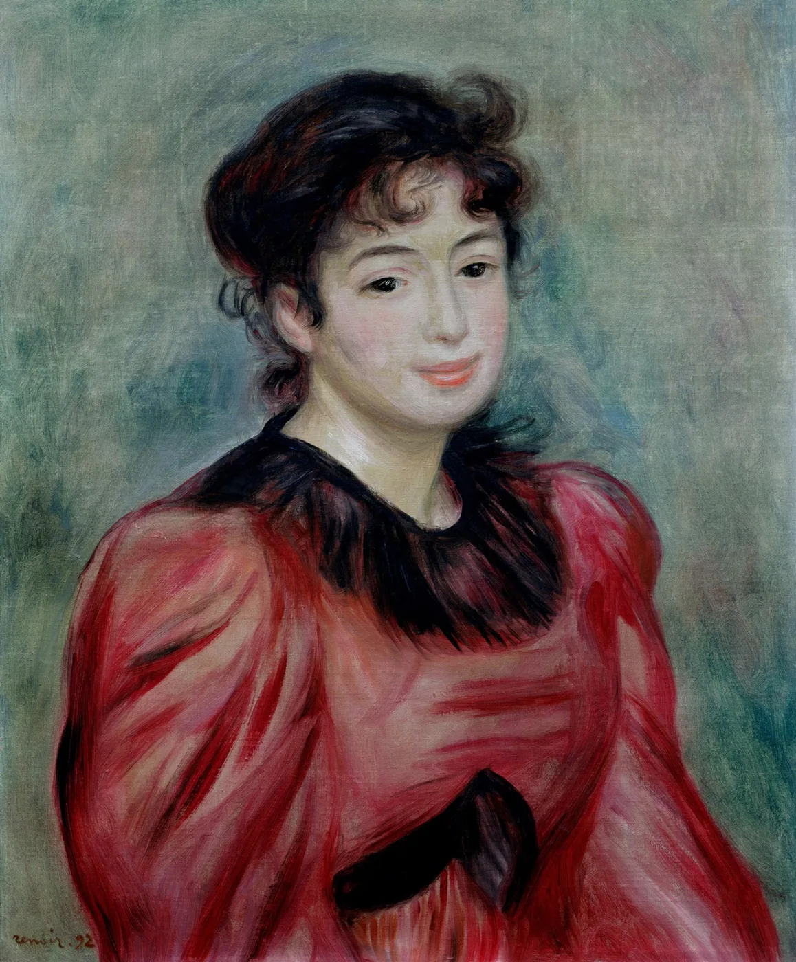A smiling dark haired young woman in a bright red dress with a black lace collar and bow is shown half length against a soft green backdrop