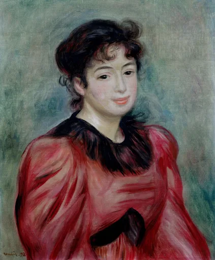 A smiling dark haired young woman in a bright red dress with a black lace collar and bow is shown half length against a soft green backdrop