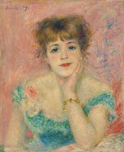 A young woman with tousled auburn hair rests her chin on her hand in a soft green dress against a pink background