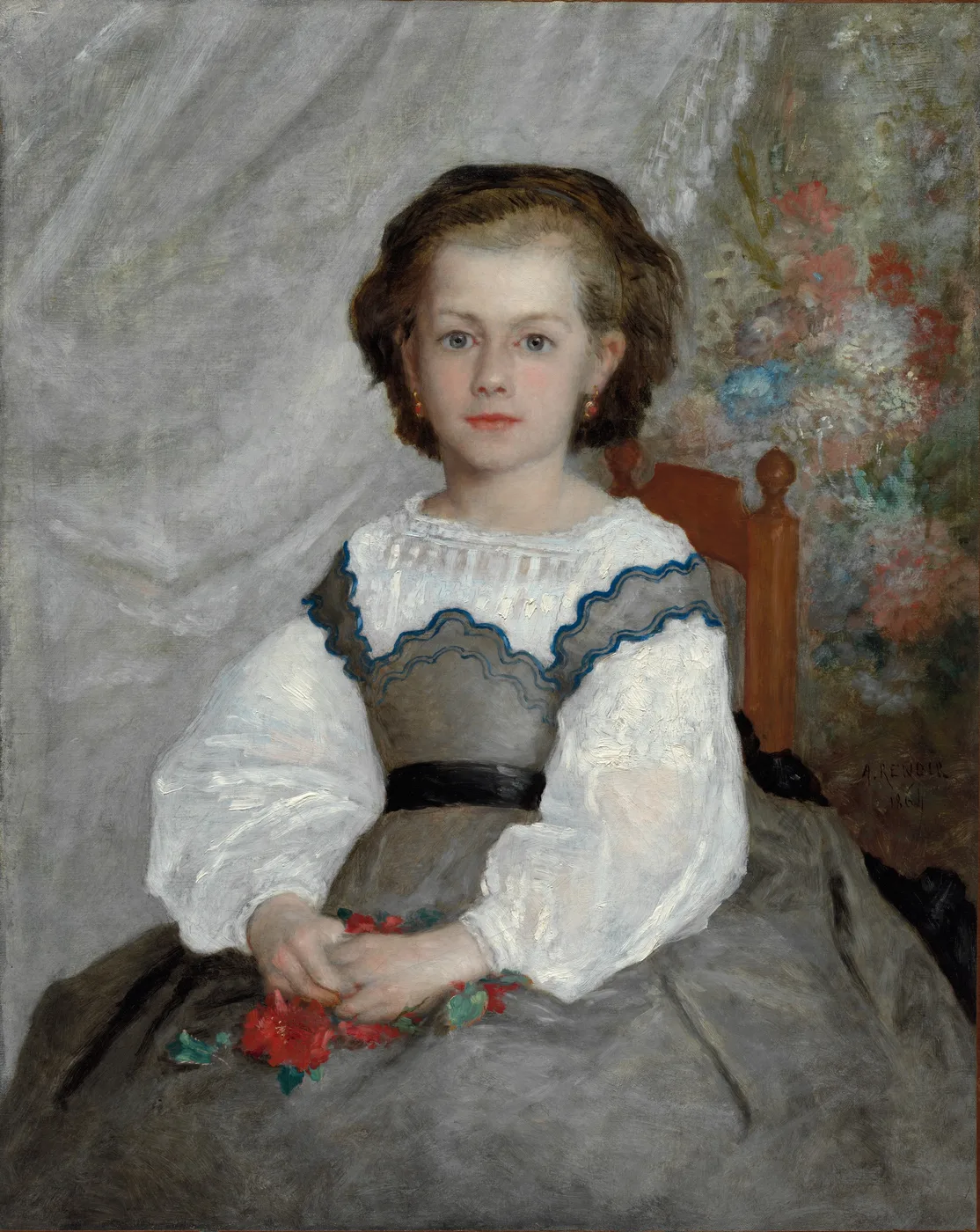 A young girl in a grey and white dress holding red flowers, seated before a bouquet on a grey backdrop, in soft grey, white, and red