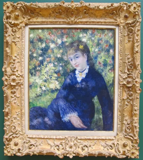 A woman in a navy dress with a white lace collar sits amid a garden of red, white and blue blossoms.