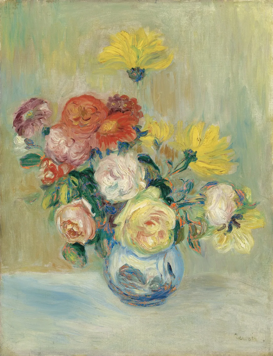 A round blue glass vase overflowing with roses in cream, pink, and red, alongside yellow dahlias, set on a pale tabletop against a soft green background.